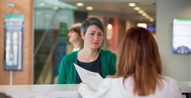 photo of woman frowning talking to a receptionist in a medical setting